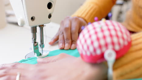 diseñadora de moda biracial cosida de tela con máquina de coser en el estudio, cámara lenta