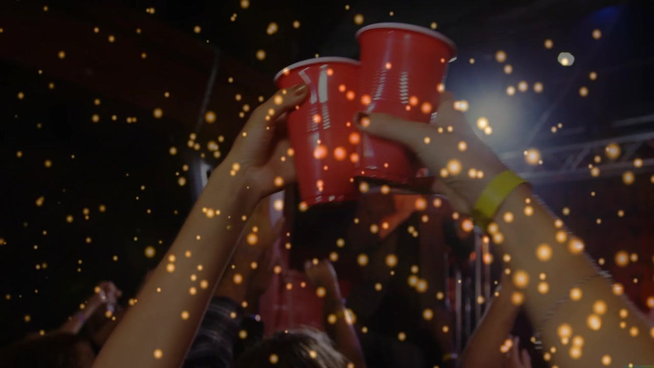 Singer cueing crowd in concert, toasting with red cups, camera moving to cups, gold overlaying cups