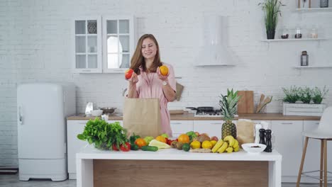 woman with orange and apple in her hands indoors. beautiful housewife chooses an apple to eat. healthy food concept.