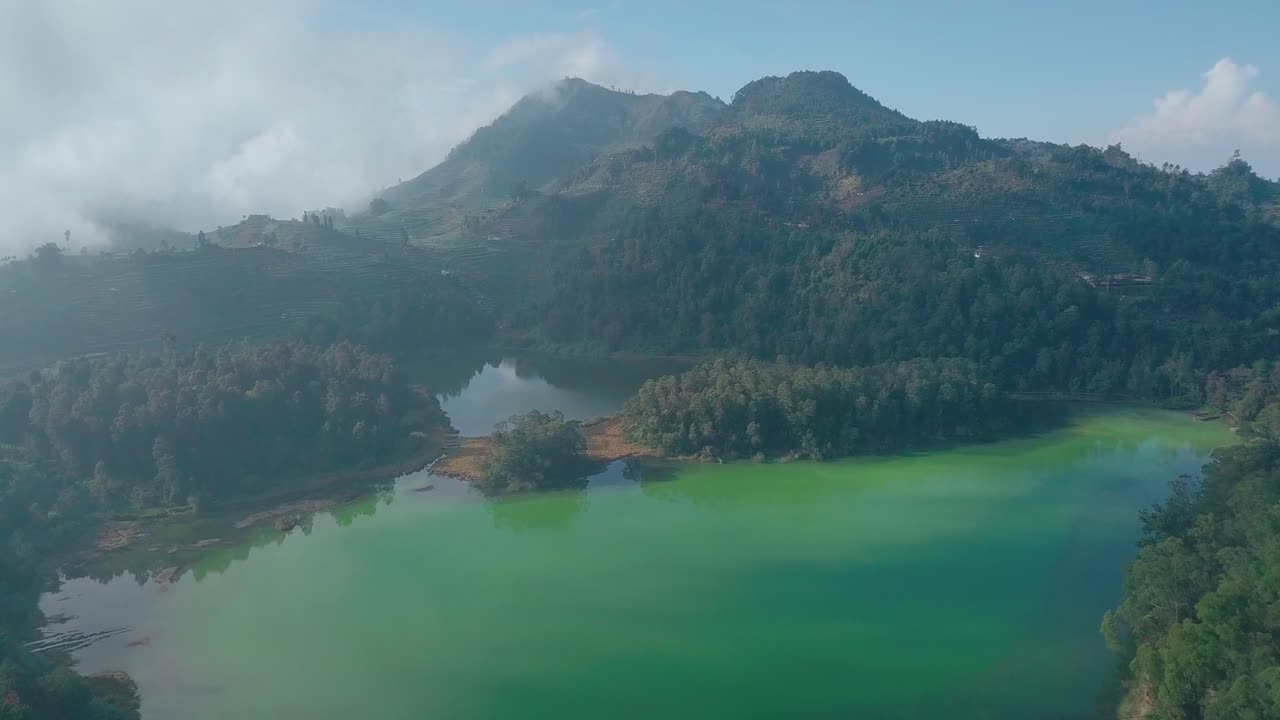 sobrevuelo aéreo lago natural y montañas forestales en segundo plano durante un denso día de niebla
