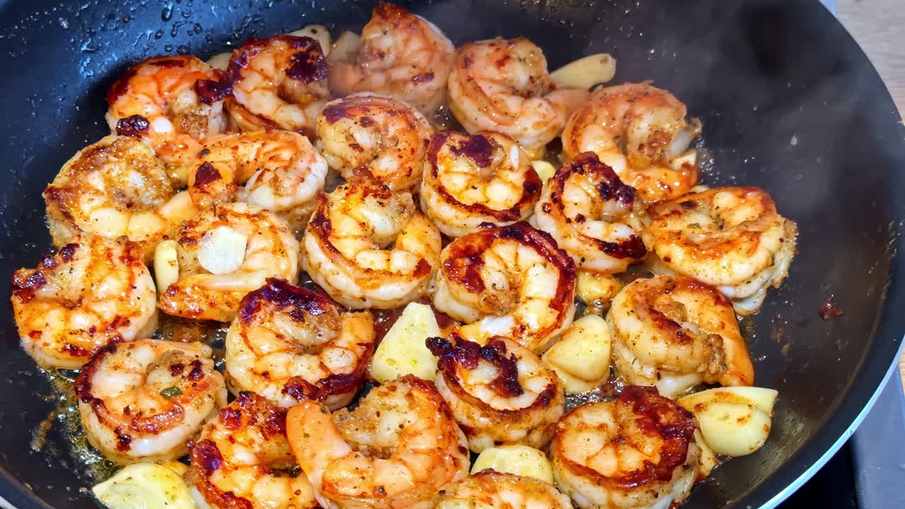 Gamberi al burro e aglio che sfrigolano in una padella, scottati con spezie e bordi dorati per una ricca scena di cucina di mare con sapore deciso e texture in primo piano.