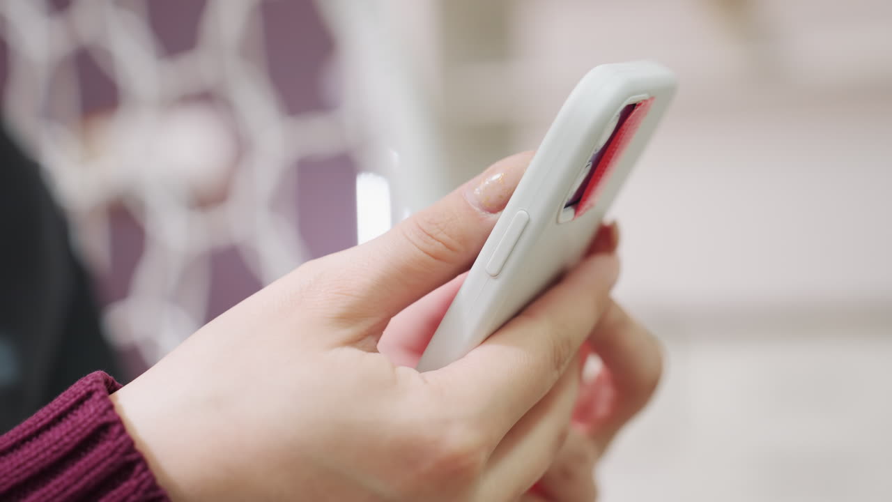 손으로 휴대폰을 스와이프하는 모습, 휴대폰에서 디지털 콘텐츠를 탐색하는 손의 디테일 뷰, 아늑한 가정 환경에서 스마트폰으로 소셜 미디어 피드를 스크롤하는 손을 포착한 클로즈업 샷