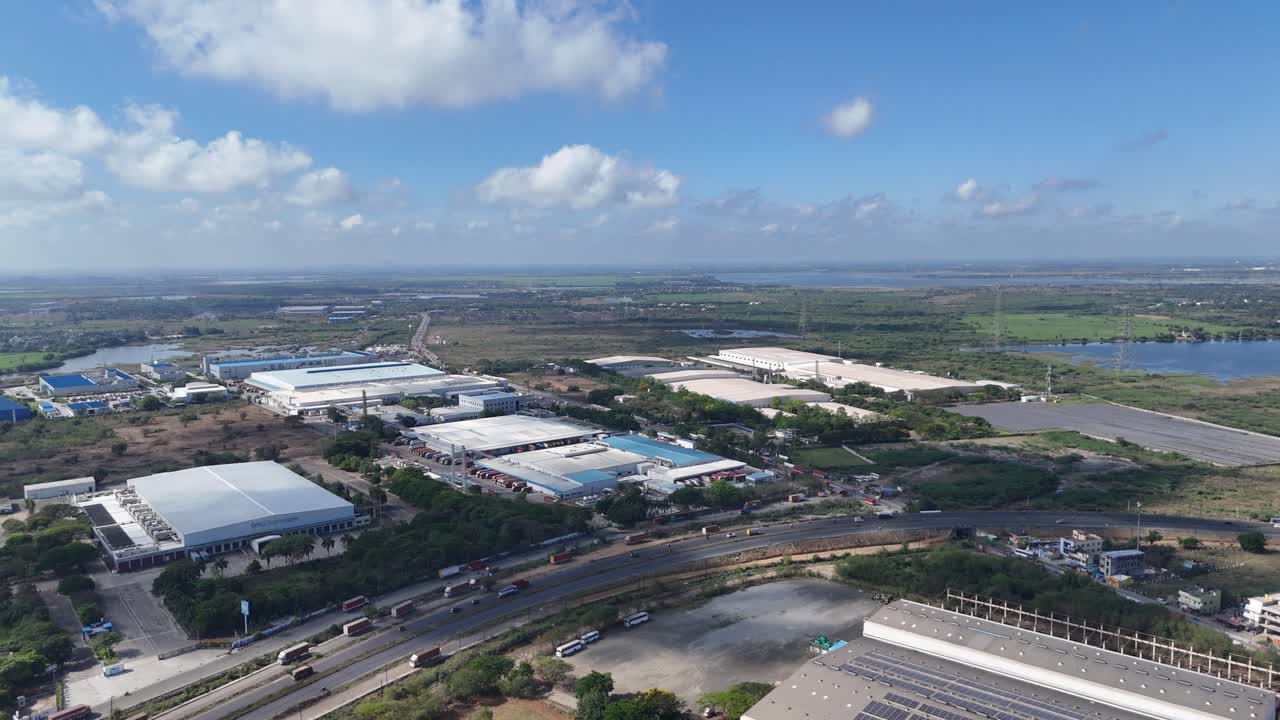 This aerial stock footage captures an expansive view of a large industrial park situated amidst a significant natural landscape on the outskirts of Chennai