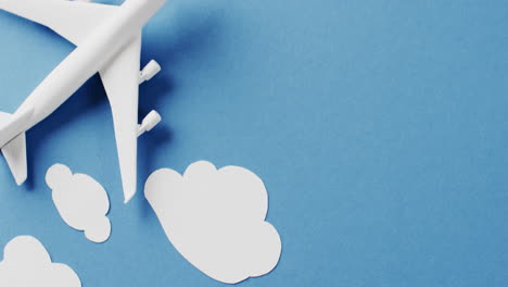 close up of white airplane model with white clouds and copy space on blue background
