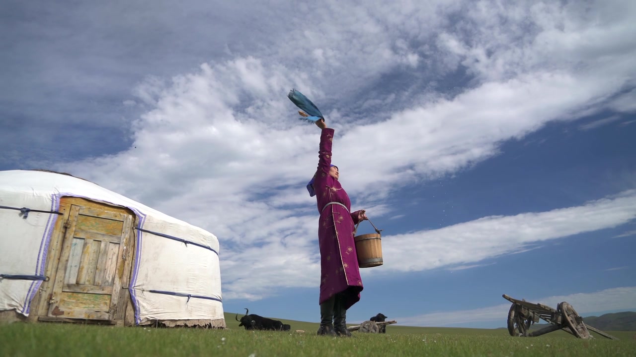 Mongolian Woman in Traditional Clothing Milking Yak Outside Yurt
