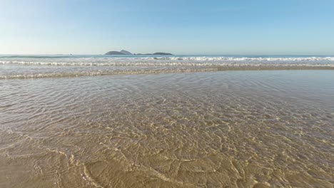 time lapse of low angle at the atlantic shore with clear water waves coming in at sunrise with the islands just outside of ipanema beach in rio de janeiro on the horizon