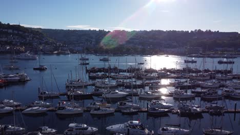 a rising shot showing many pontoons and marinas in a beautiful harbour whilst the evening sun is just starting to sit behind the hills