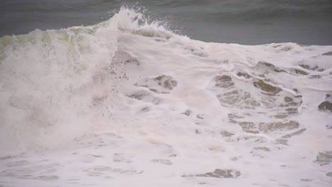 olas a cámara lenta con espuma blanca en medio de una tormenta en el océano