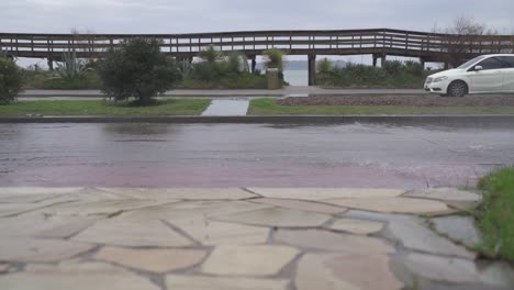 Lateral-View-Of-Car-Driving-By-Flooded-Street,-Punta-Del-Este,-Uruguay