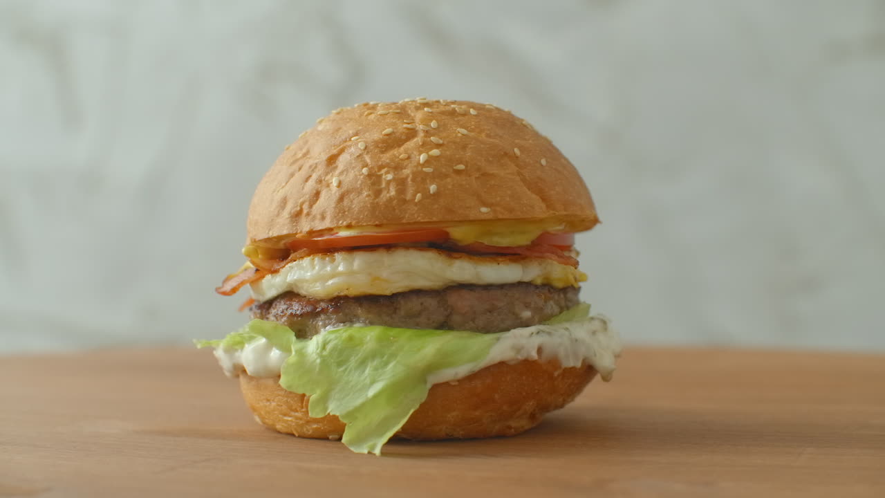 yummy concepto de comida rápida. hamburguesa fresca a la parrilla casera con carne patata tomates pepino lechuga cebolla y semillas de sésamo. estilo de vida no saludable. fondo de la comida.