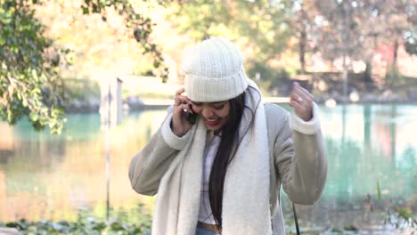 Mujer-Recibe-Buenas-Noticias-Durante-Una-Llamada-Telefónica-En-Un-Parque-De-La-Ciudad-Durante-La-Fría-Temporada-De-Otoño-Y-Otoño