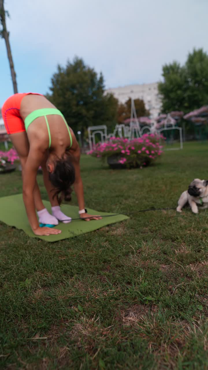 mujer practicando yoga en un parque con su perro pug