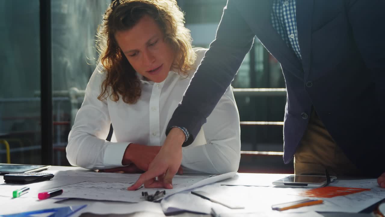 Homem sentado estudando planos e seguindo o colega que aponta, com selos de dados aparecendo, orientando os negócios