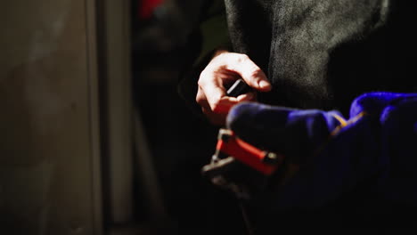 close view of a gloved hand operating a crane's remote control in a shadowy industrial workspace