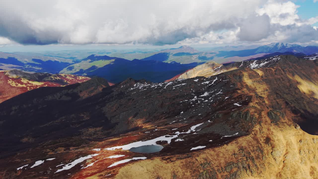 Aerial shot of Dolomites Mountains, showcasing rocky peaks, snow, and vast terrain