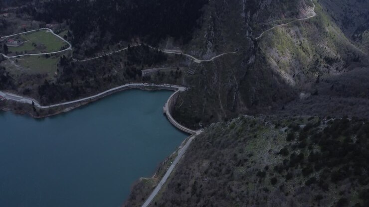 Lenta ripresa aerea cinematografica distante di una diga che separa un lago e un canyon nella Grecia centrale | 4K