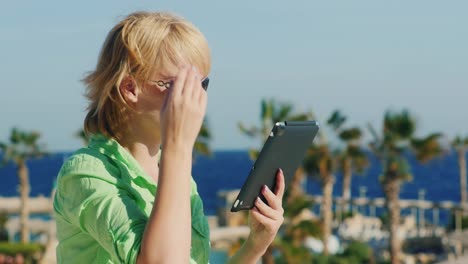 Ein-Tourist-Mit-Sonnenbrille-Genießt-Das-Tablet-Vor-Dem-Hintergrund-Einer-Tropischen-Landschaft
