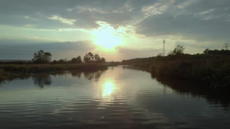 Niedrige-Drohnenaufnahme-In-Der-Nähe-Des-Flusses-Bei-Sonnenuntergang