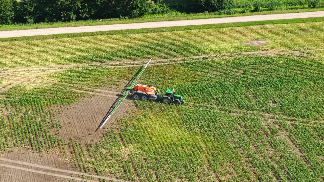 Aerial of tractor spraying dry farmland in summer, creating lines across soil