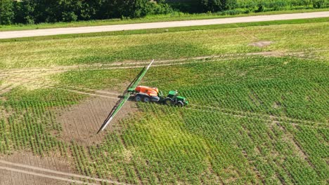 aerial of tractor spraying dry farmland in summer, creating lines across soil