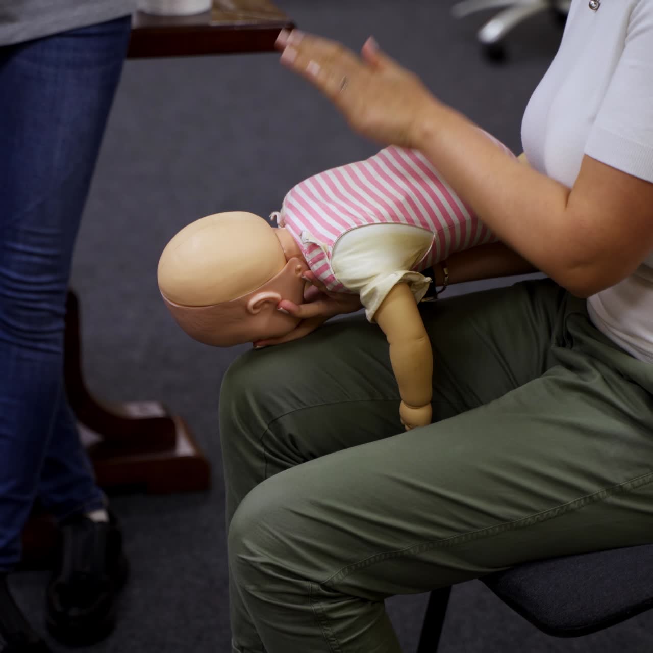 Practical course on a doll dummy. Female practitioner teaching to reanimate patient on a baby mannequine. Instructor demonstrate the training exercise