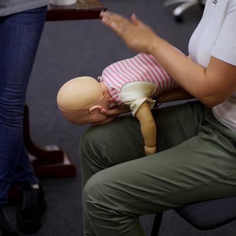 practical course on a doll dummy. female practitioner teaching to reanimate patient on a baby mannequine. instructor demonstrate the training exercise