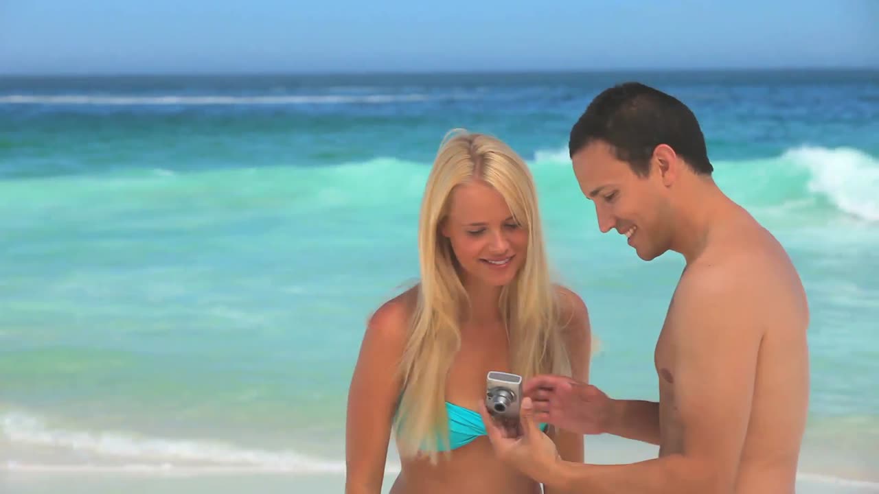 hombre tomando una foto de sí mismo y su novia en la playa