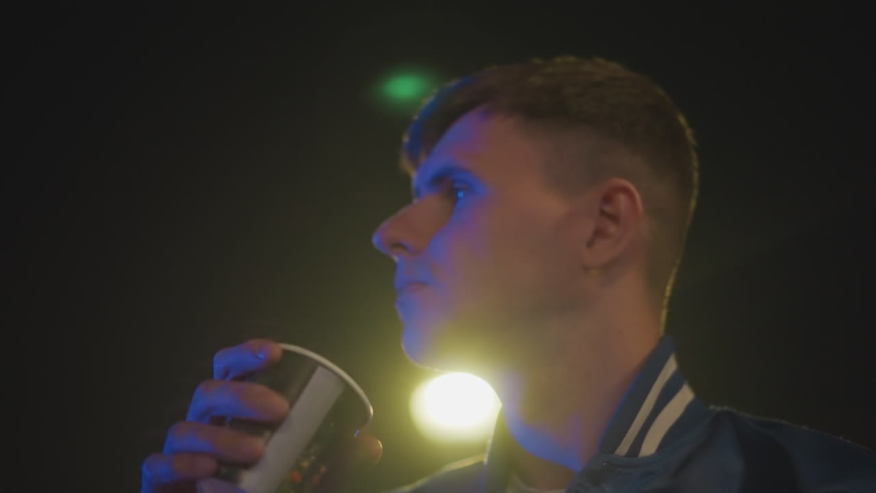 Nighttime city scene, Cinematic image of driver under blue light, Reflective profile of driver illuminated by neon glow, Quiet city scene featuring driver gazing upward in neonlit environment