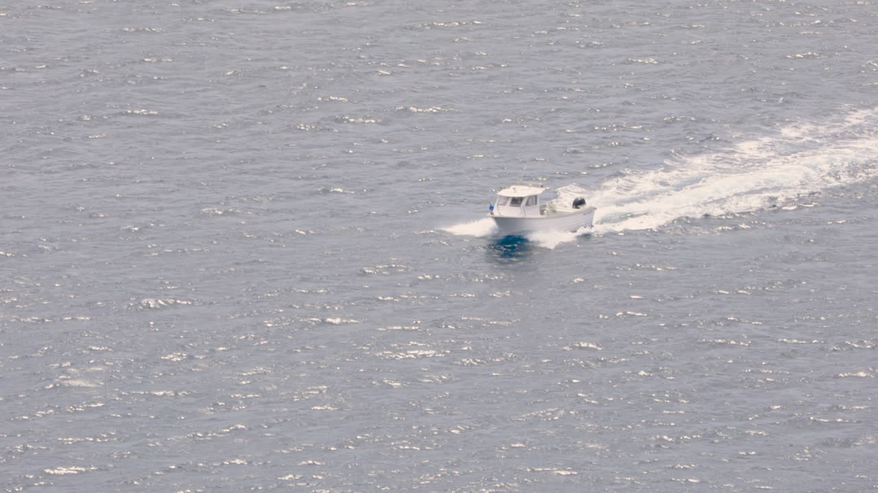 밝은 여름날 작은 흰색 어선이 잔잔한 물을 가로지른다