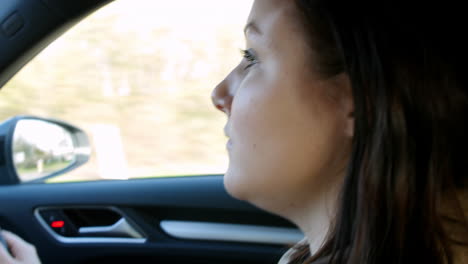 young woman driving in a car in a rural setting, head shot