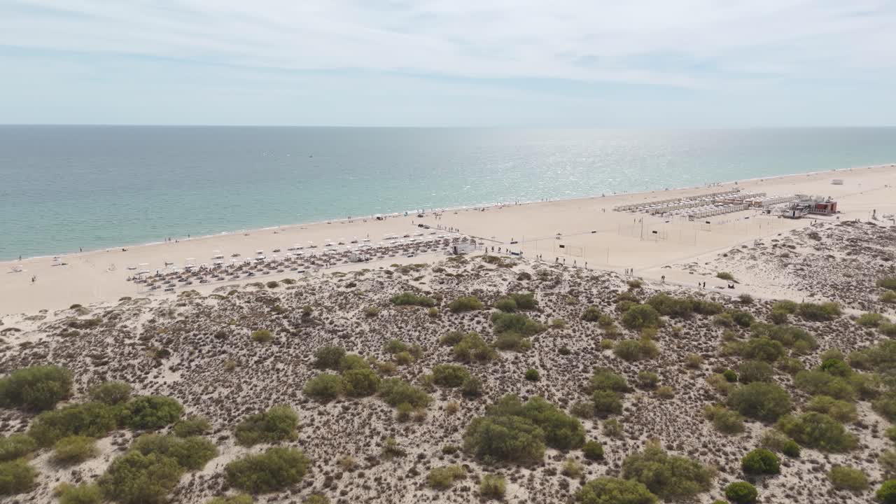 Flying over natural sand dunes on Tavira Island, Portugal, approaching the pristine beach and turquoise waters