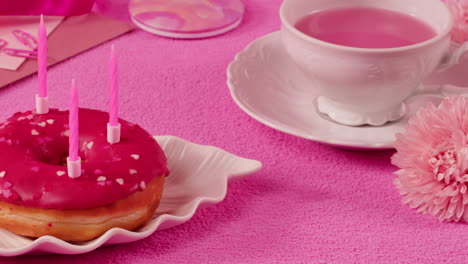 pink birthday donut with tea and flowers