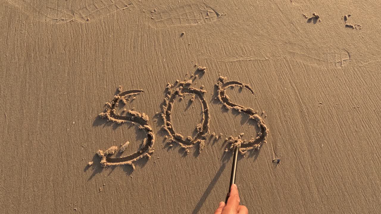 &amp;quot; sos &amp;quot; word is written by hand on the beach sand ,save our souls