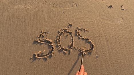 „SOS“-Wort-Ist-Von-Hand-Auf-Den-Strandsand-Geschrieben,-Rette-Unsere-Seelen