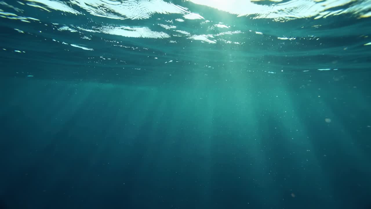 Raggi di sole che penetrano la superficie calma dell'oceano, illuminando lo spazio sottomarino blu intenso con una pacifica atmosfera naturale