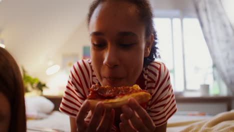 chicas adolescentes disfrutando de pizza en una cama