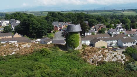 Llangefni-hillside-windmill-ivy-covered-landmark-aerial-view-overlooking-Welsh-Snowdonia-mountains,-Anglesey