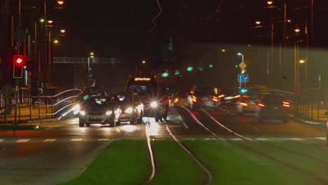 Timelapse-of-city-rush-hour-traffic-on-the-street-of-Liepaja-tram-bridge,-traffic-light-streaks,-tram-rails-with-fast-moving-trams,-distant-medium-shot