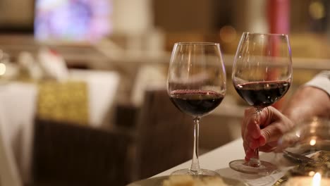 two glasses of red wine clink together in a softly lit restaurant, creating a warm and intimate atmosphere