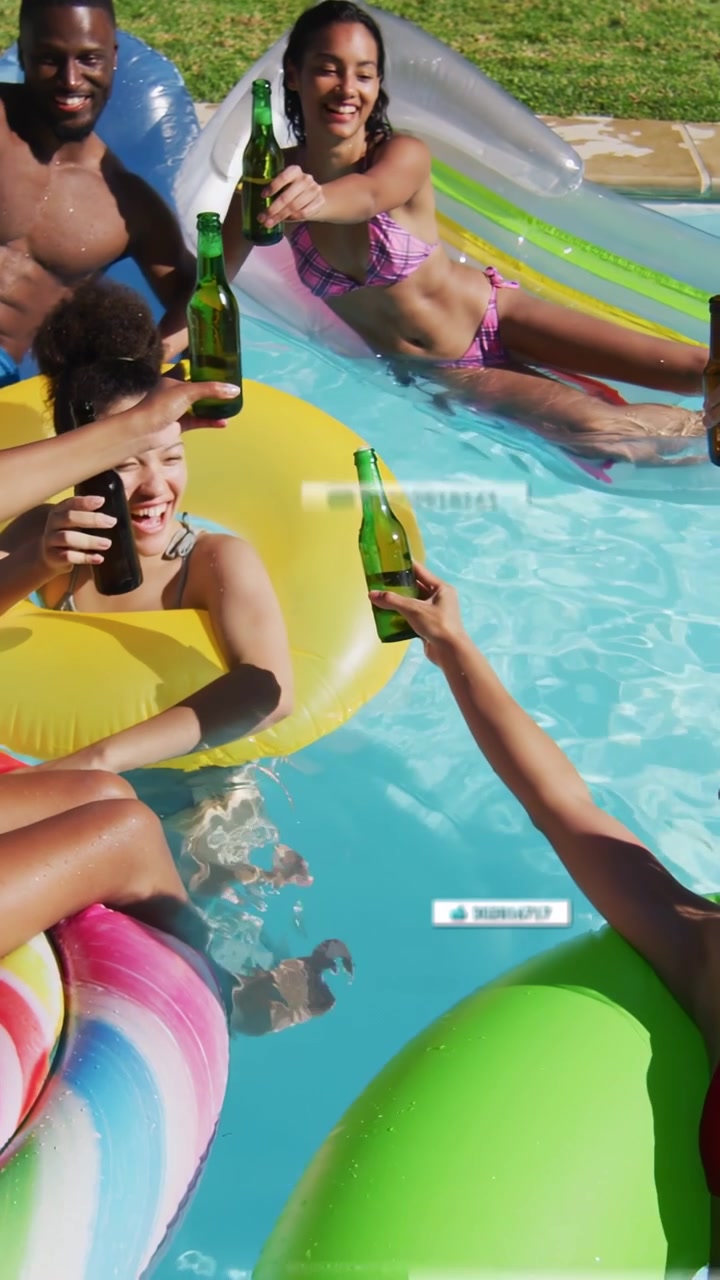 Video verticale: Amiche in bikini che brindano sollevando bottiglie verdi in una piscina domestica, con suggerimenti da tag dell'interfaccia utente.