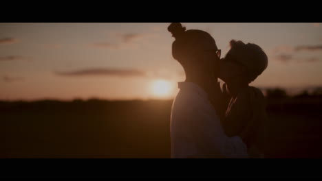 una pareja besándose al atardecer.