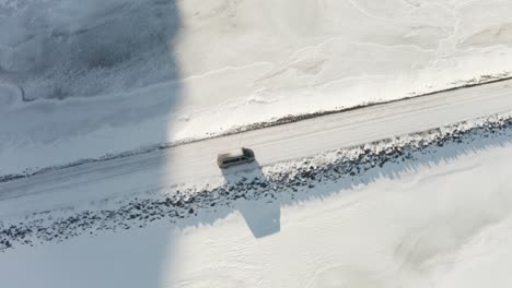 a tracking shot for a gray car traveling in the middle of the snow