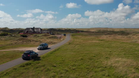 Auto-Fährt-Auf-Schmaler-Straße-Und-Fährt-An-Einem-Anderen-Fahrzeug-Und-Gebäude-Vorbei.-Panoramablick-Auf-Die-Flache-Landschaft.-Dänemark