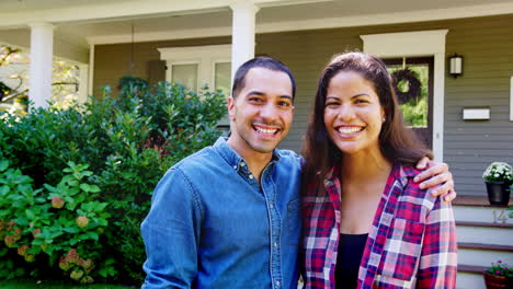 Retrato-De-Una-Pareja-Sonriente-Parada-Frente-A-Su-Casa