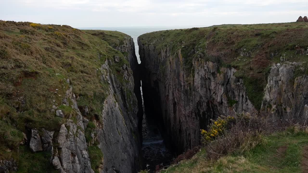 agua del océano entrando en el salto del cazador a través de la roca de piedra caliza, gales