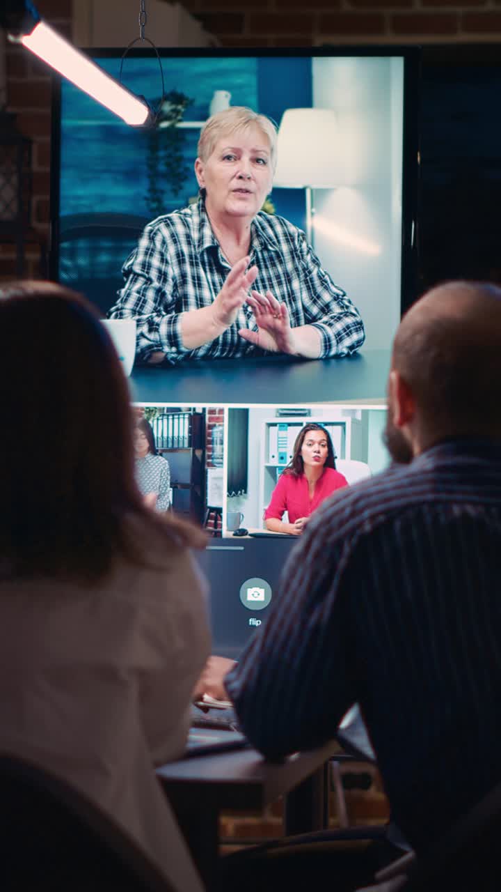 Vertical video: Employees greeting mid adult coworker in videocall, waving hi