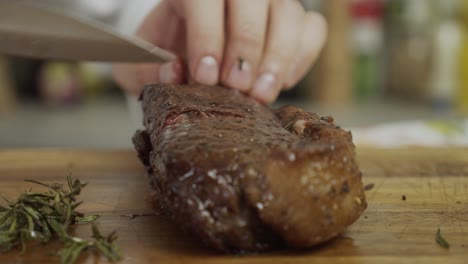 chef cuts freshly fried steak on cutting board with steel knife