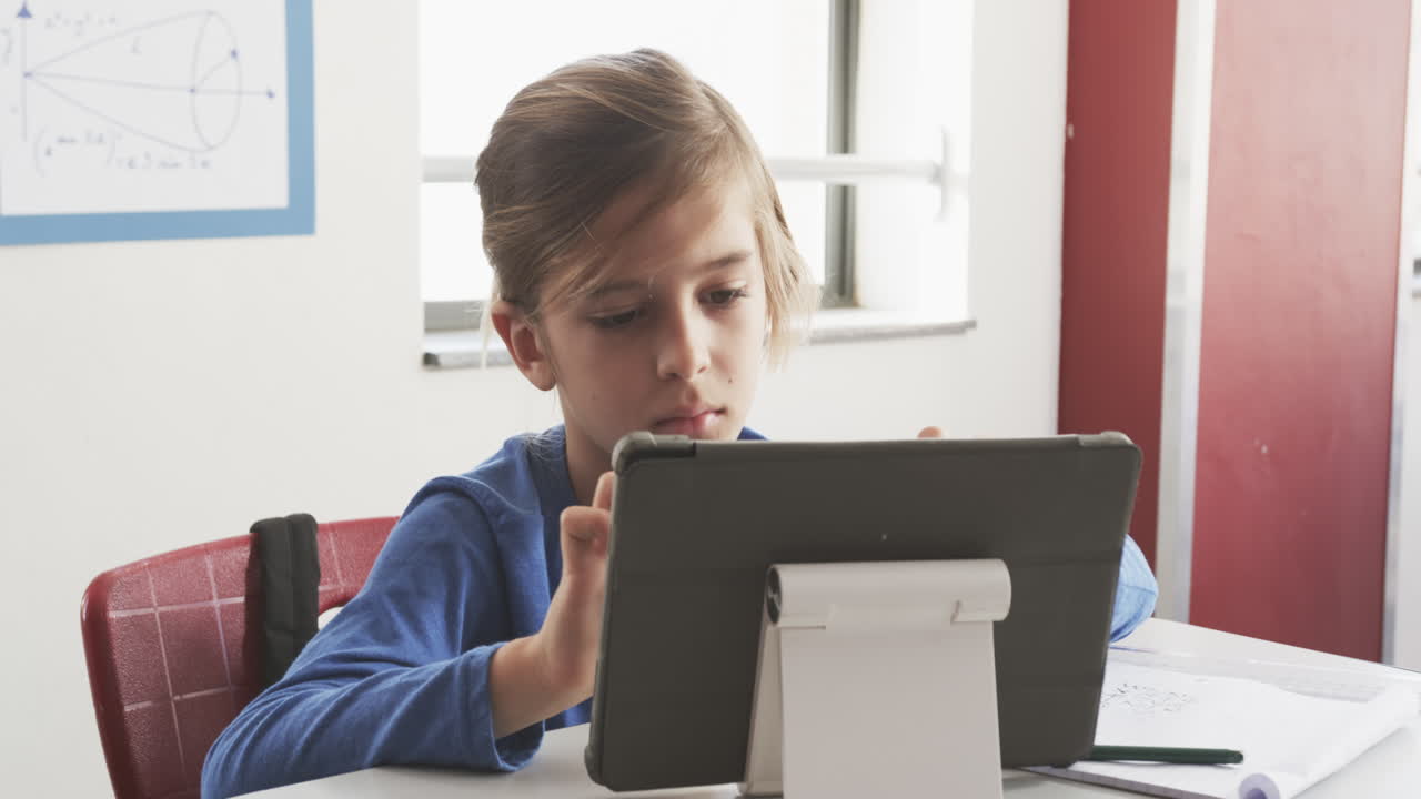 In school, boy using tablet for studying at desk in classroom