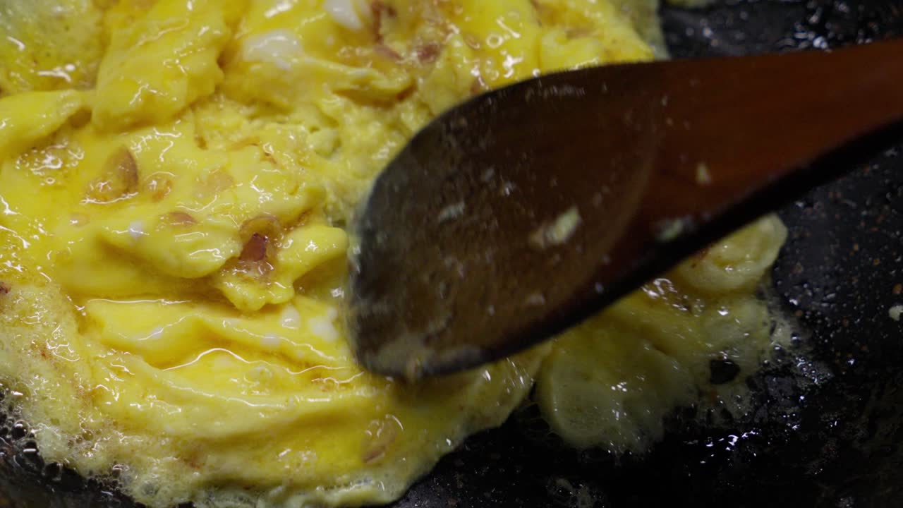 Cooking scrambled eggs in a pan, close-up view with stirring