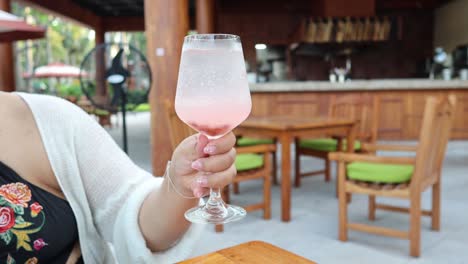 la mano de una persona levantando un vaso de bebida